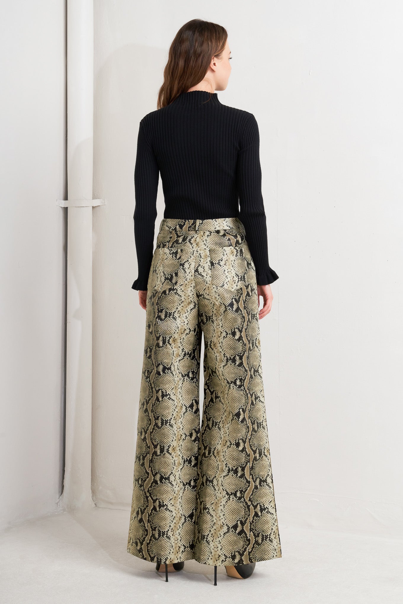 A printed faux leather pant with front closure, side pockets, and wide leg