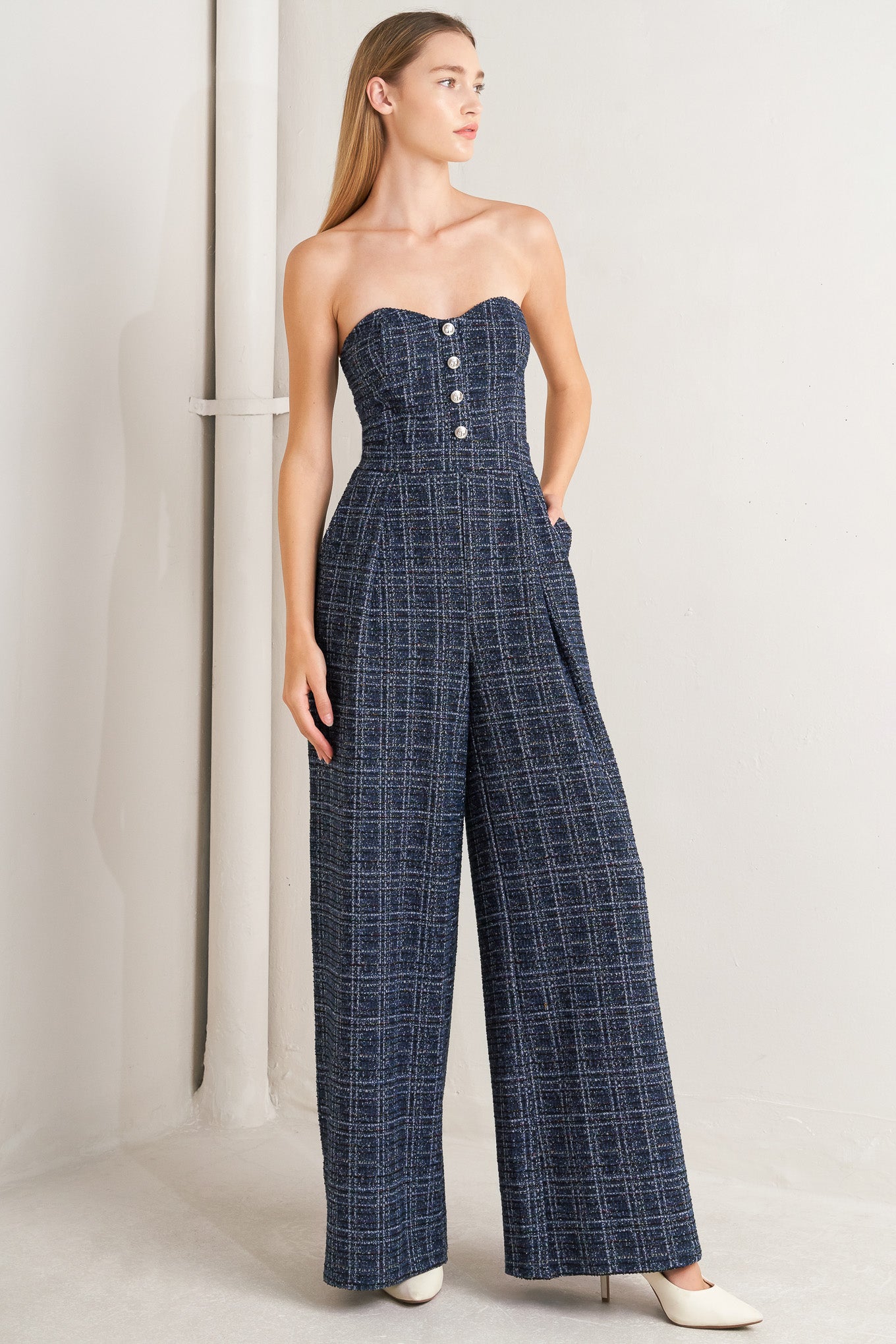 A tweed jumpsuit featuring sweetheart neckline, front button detail, side pockets and back zipper closure