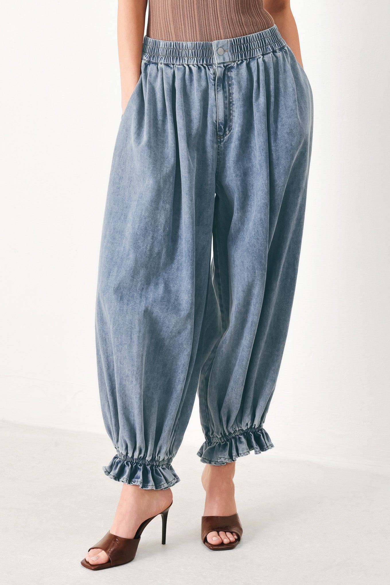 Woman wearing light blue denim genie pants with elastic waist, front closure and side pockets | FREEMARKET | Flying Tomato