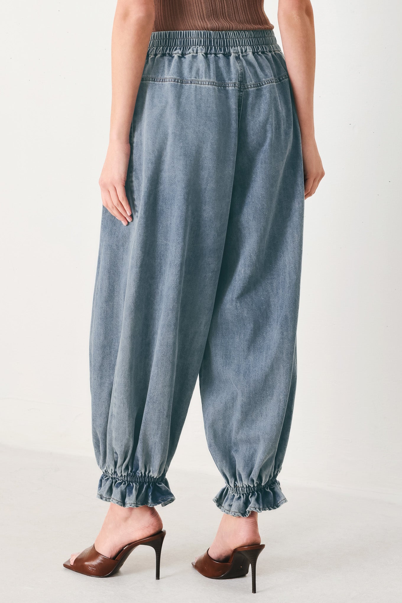 Woman wearing light blue denim genie pants with elastic waist, front closure and side pockets | FREEMARKET | Flying Tomato