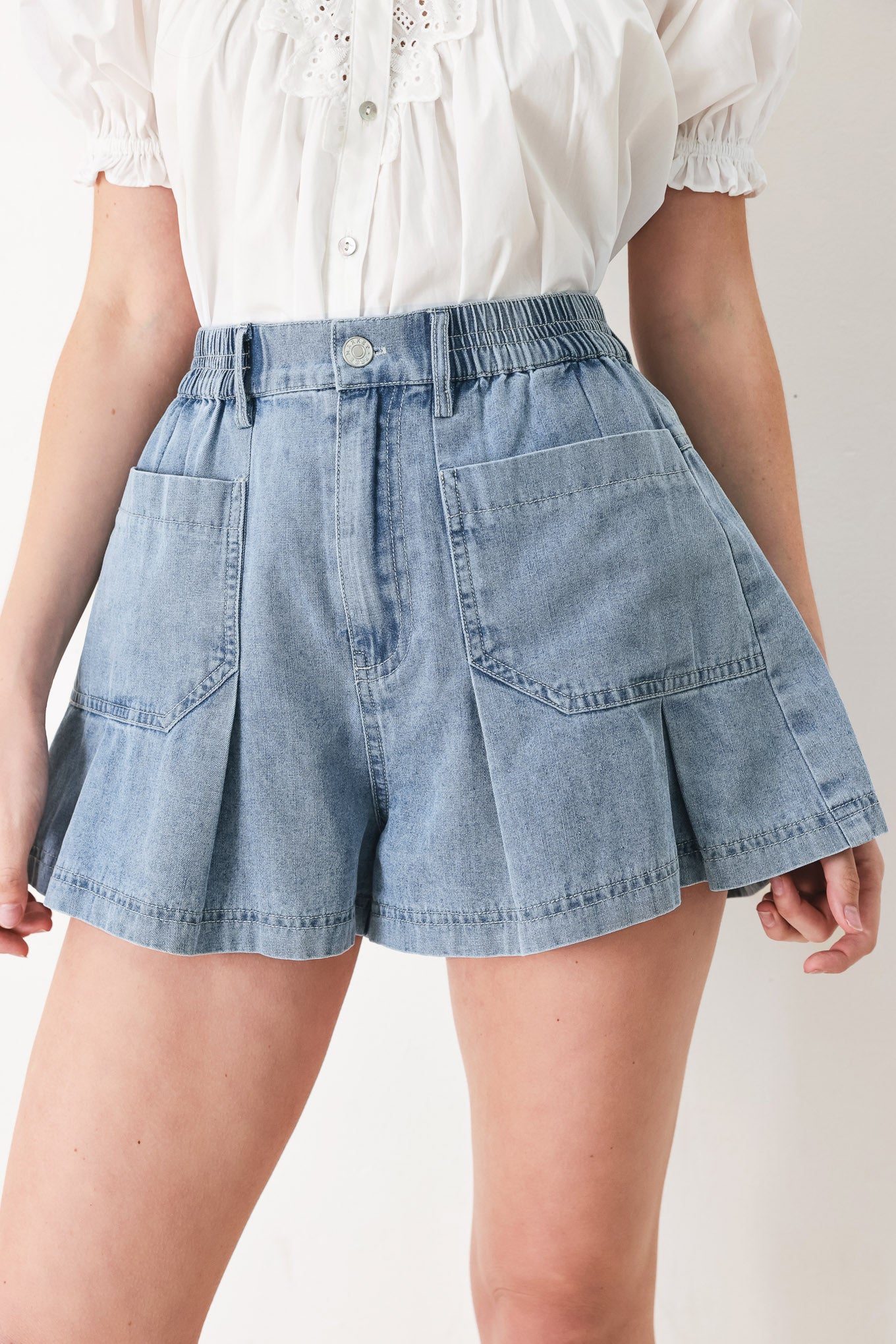 Woman wearing washed light denim short featuring elastic waist, front closure, front pockets and pleats with wide leg | FREEMARKET
