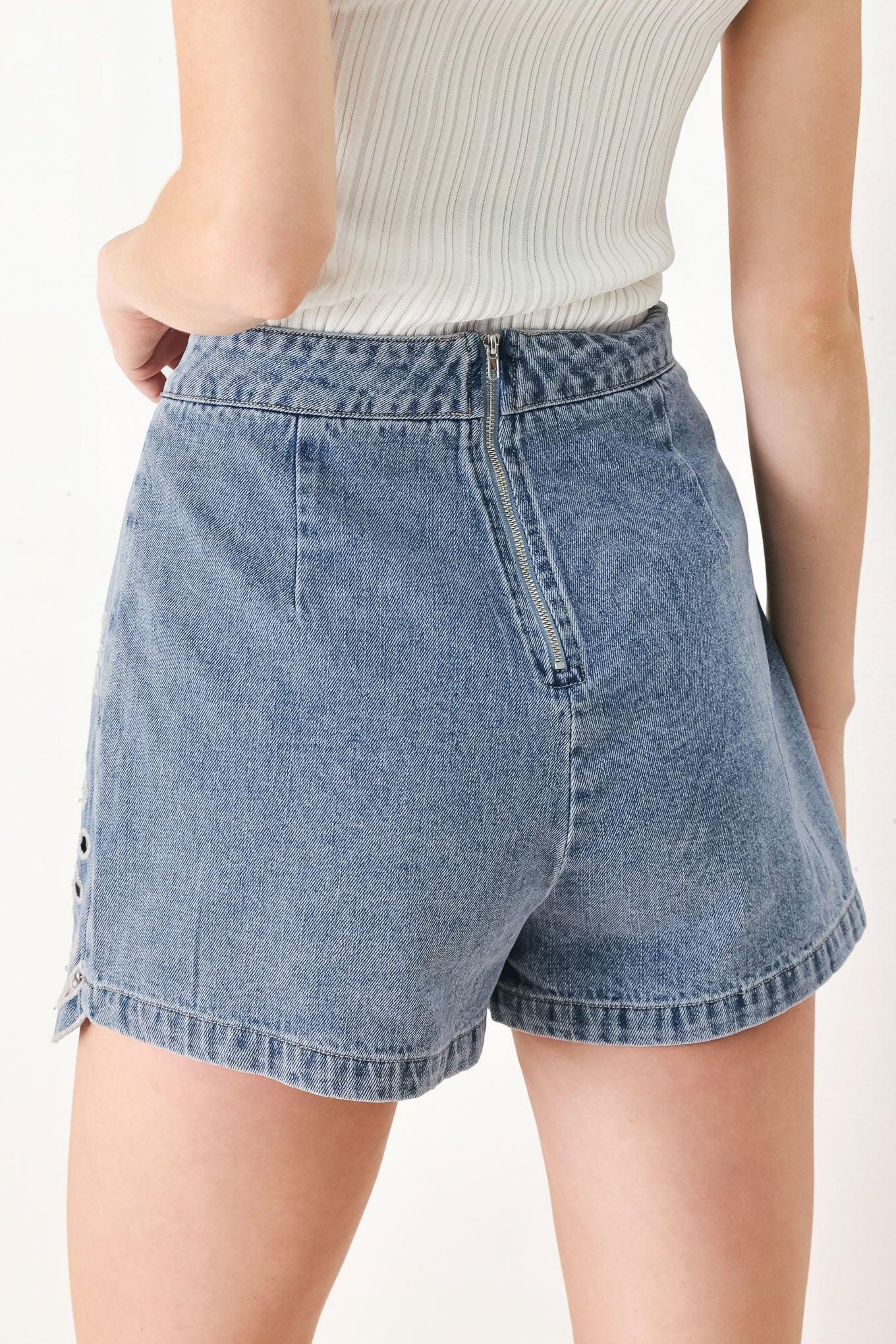 A washed denim skort with eyelet cut out hem and back zipper closure