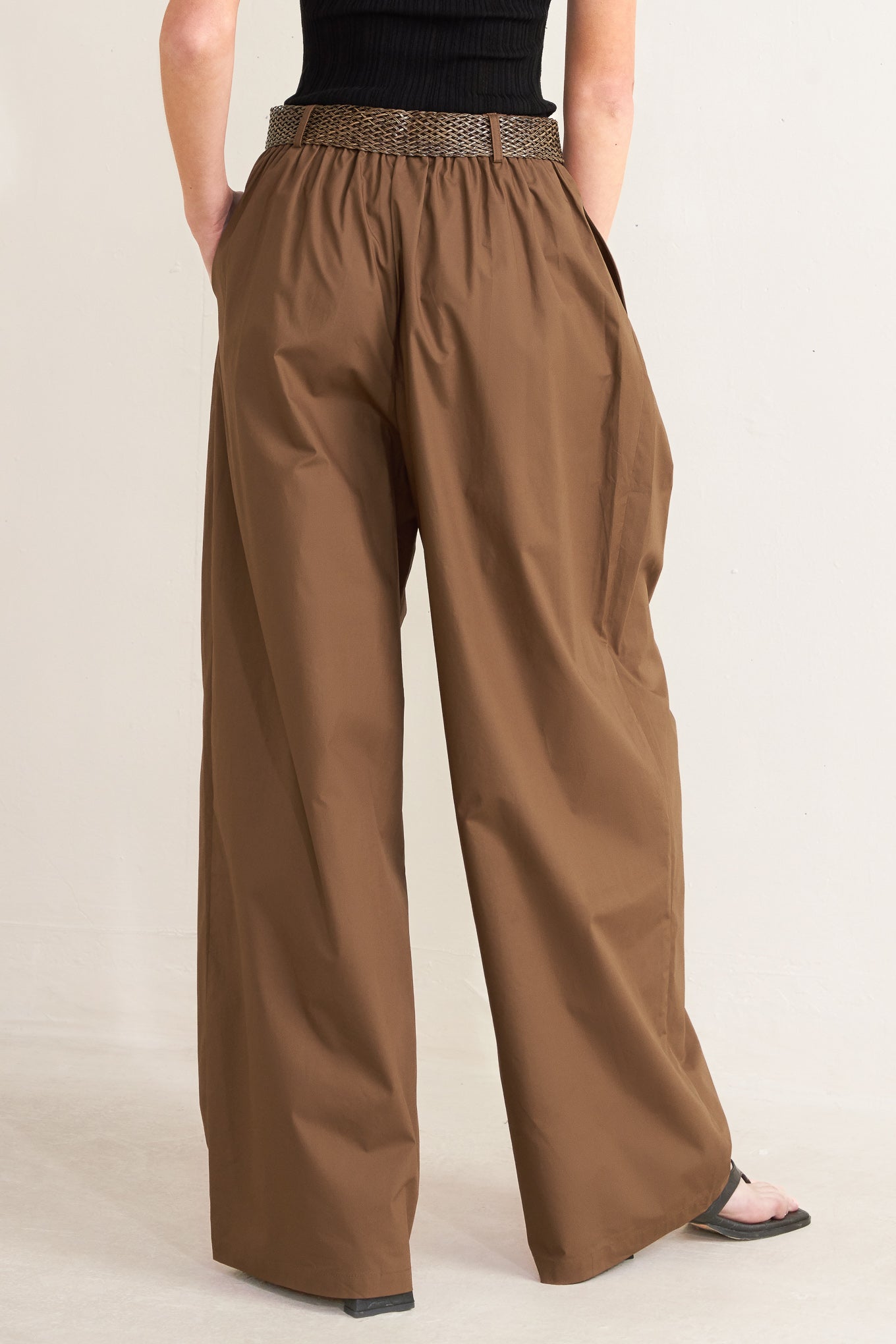Brown wide-leg pants worn by a person on a beige background