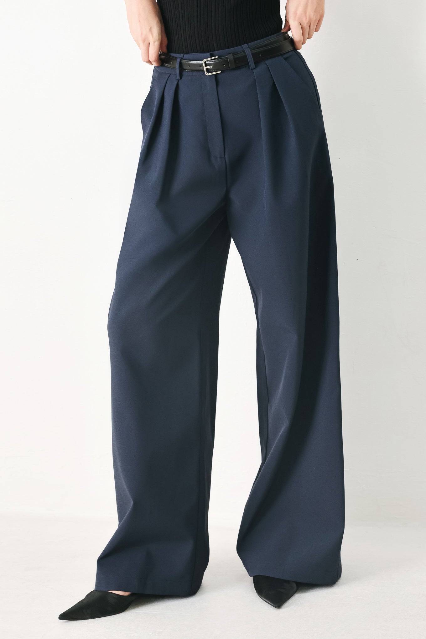 Woman wearing navy pleated pants with a black belt | FREEMARKET