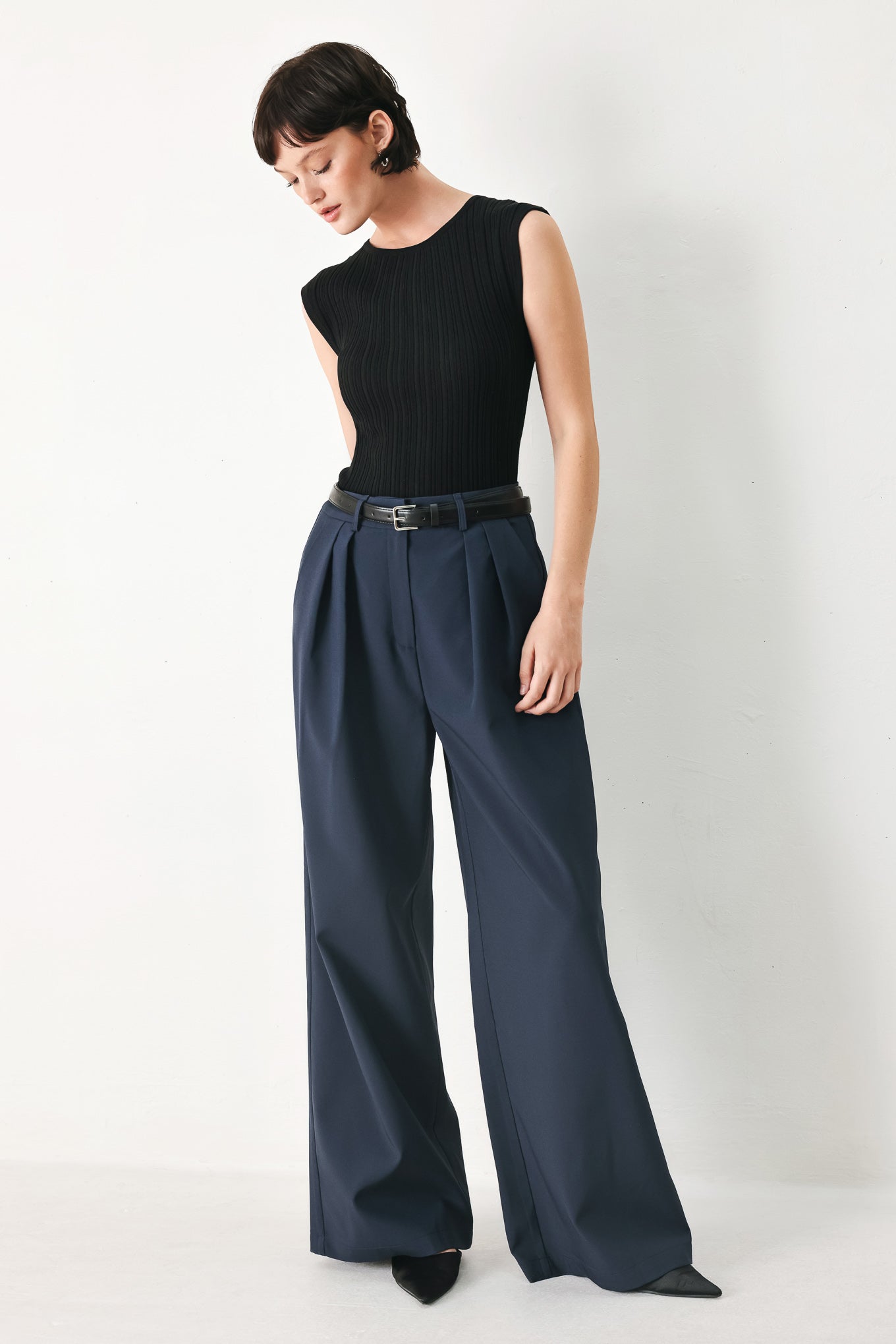 Woman wearing navy pleated pants with a black belt | FREEMARKET