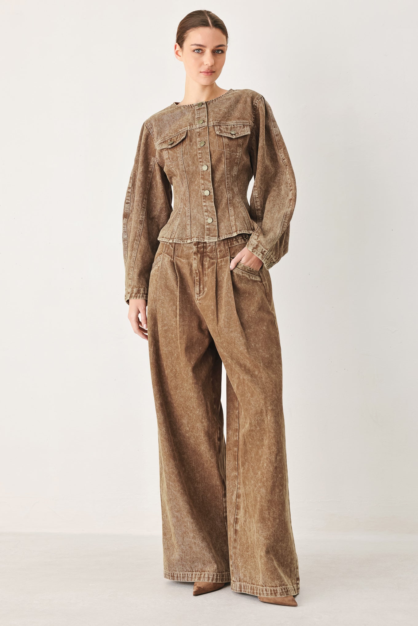 Woman wearing a washed brown denim pant featuring front closure, pockets and side buckle detail at waist | FREEMAKET