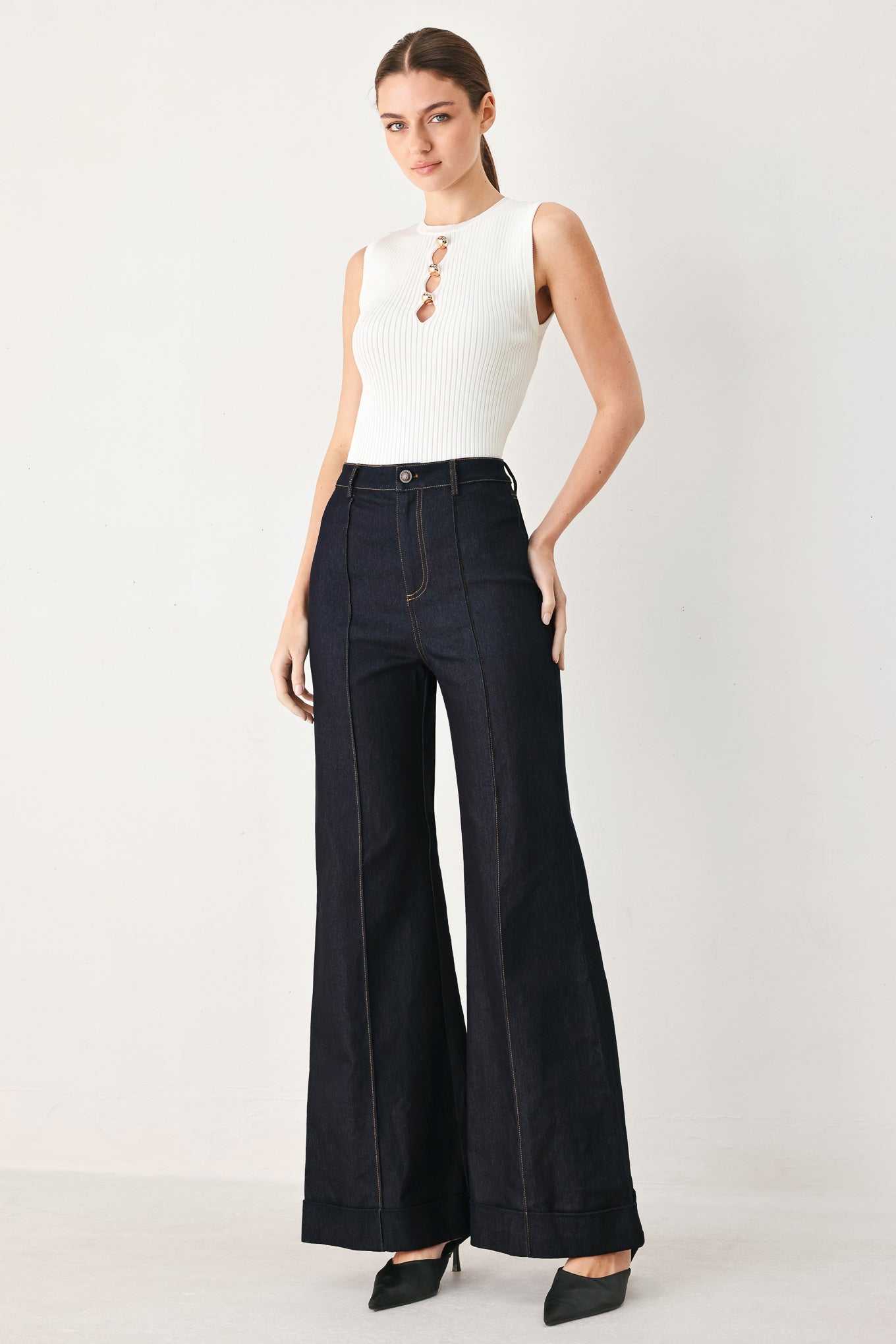 Woman wearing dark flared leg denim pants with front closure and cuff hem | FREEMARKET