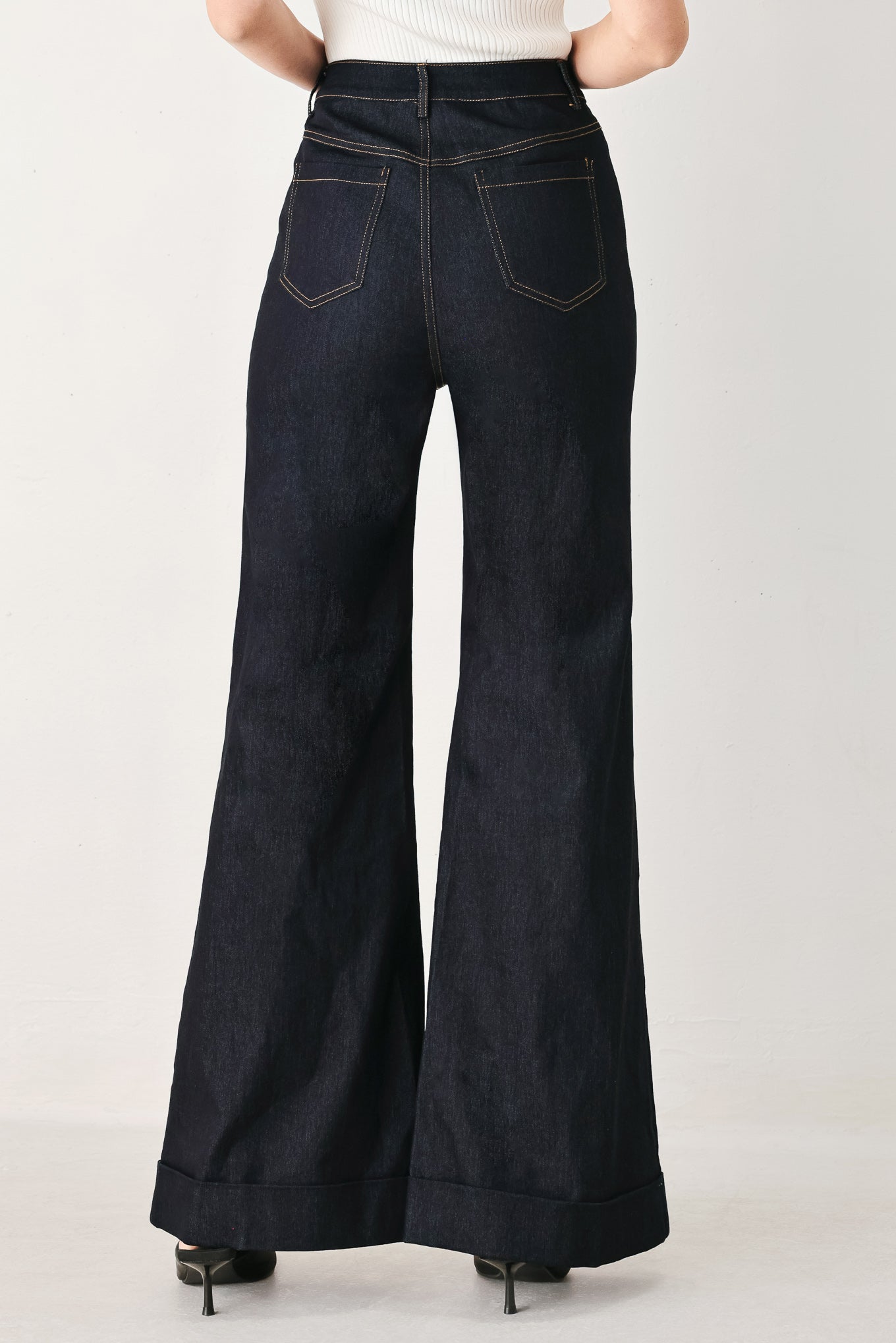 Woman wearing dark flared leg denim pants with front closure and cuff hem | FREEMARKET