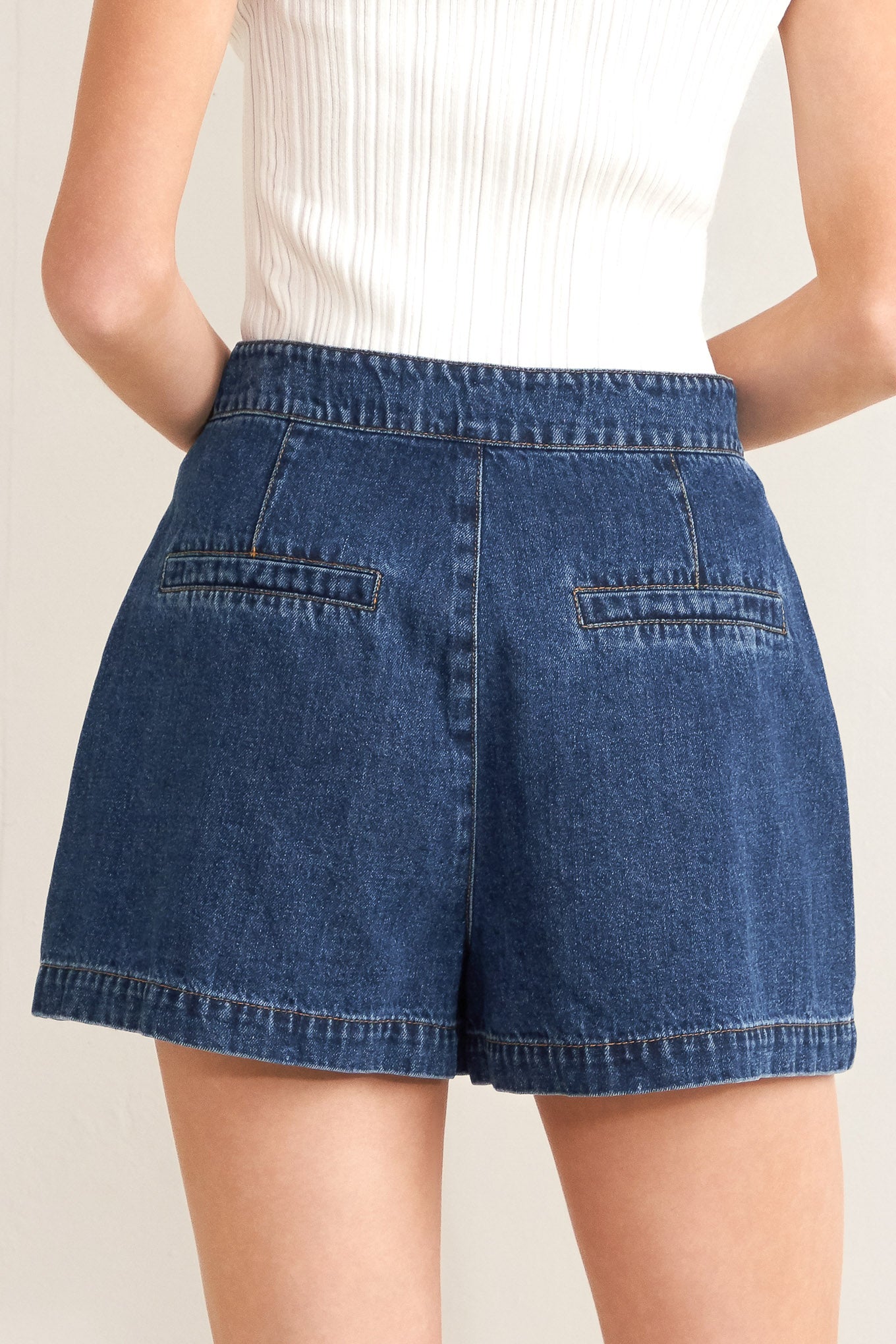 Blue denim shorts worn by a person on a beige background