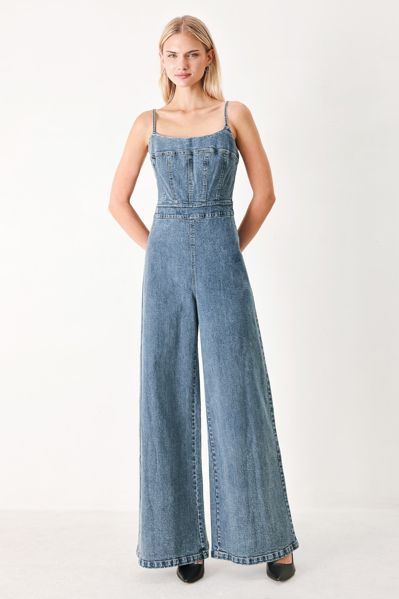 Woman wearing a denim jumpsuit featuring straight neckline, straps, wide leg and back zipper closure | FREEMARKET