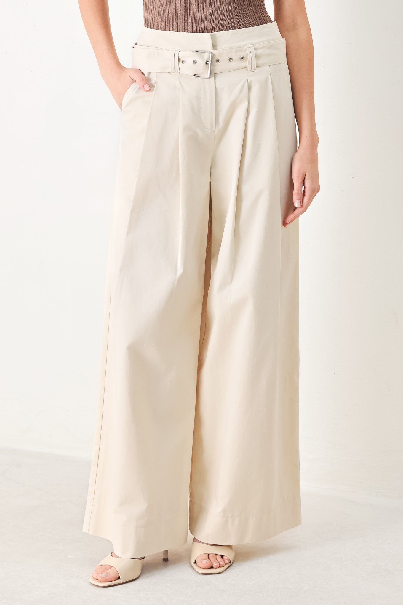 Woman wearing beige wide-leg pants with self belt, front closure and pockets | FREEMARKET | Flying Tomato