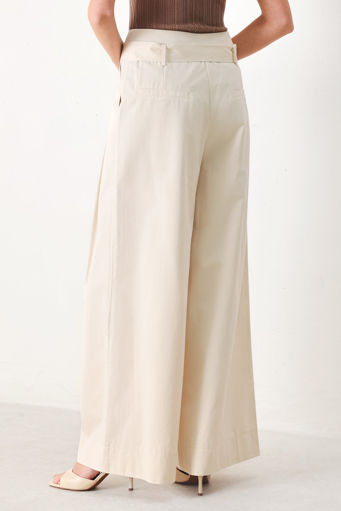 Woman wearing beige wide-leg pants with self belt, front closure and pockets | FREEMARKET | Flying Tomato