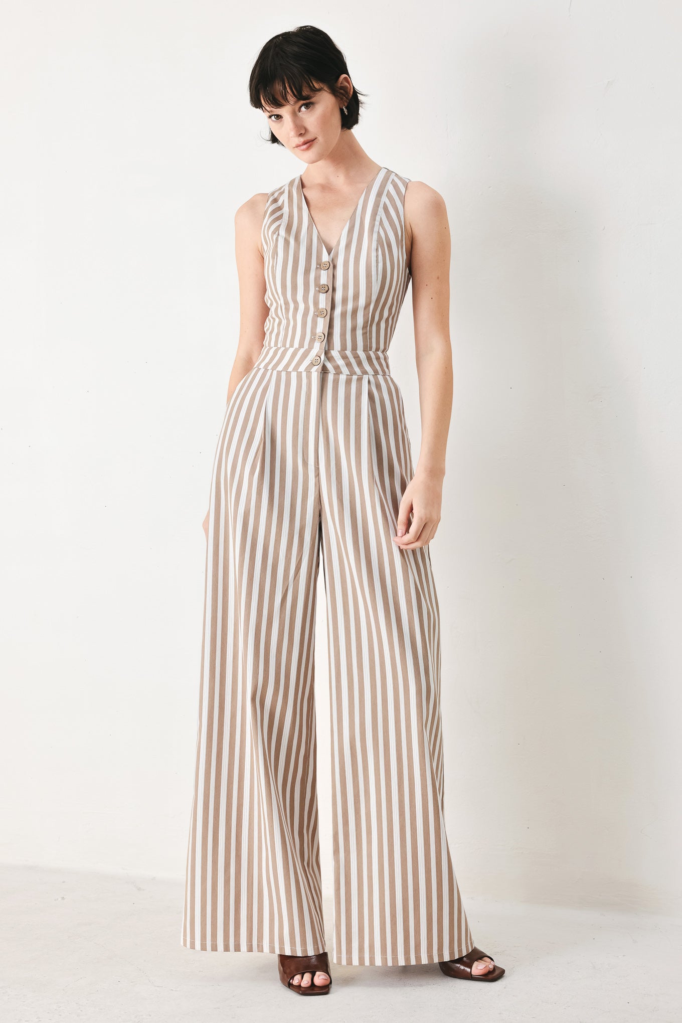 Woman wearing a striped woven jumpsuit featuring V neckline, sleeveless, front button/zipper closure and wide leg | FREEMARKET