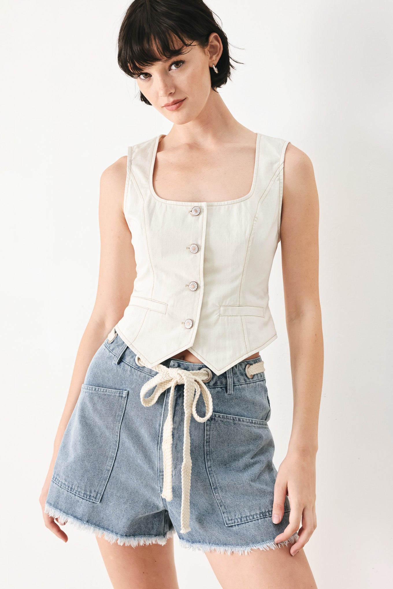 Woman wearing denim shorts with front closure, side pockets, contrasting tie with grommet and fray hem | FREEMARKET