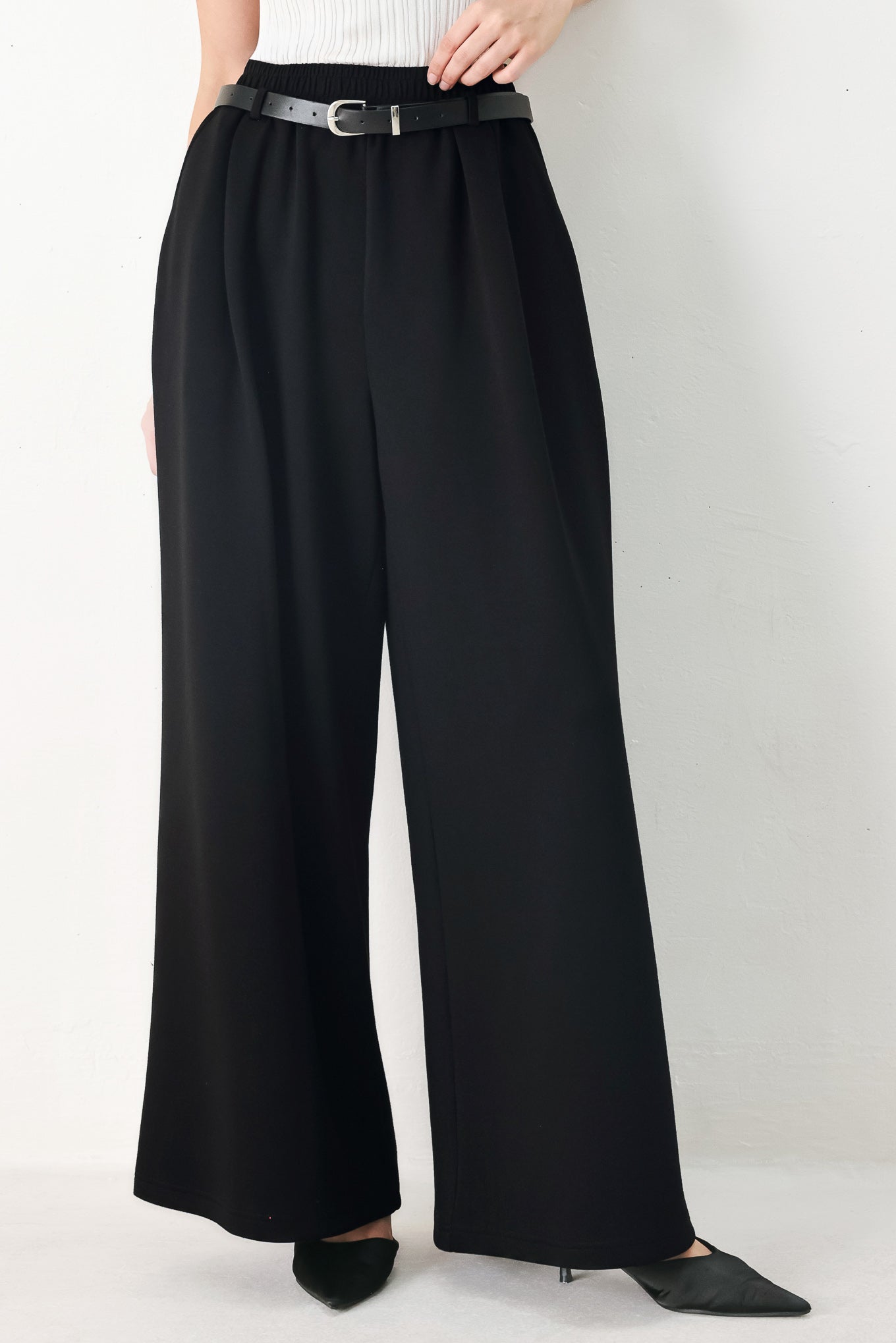 Woman wearing black wide-leg pants with a self tie belt | FREEMARKET