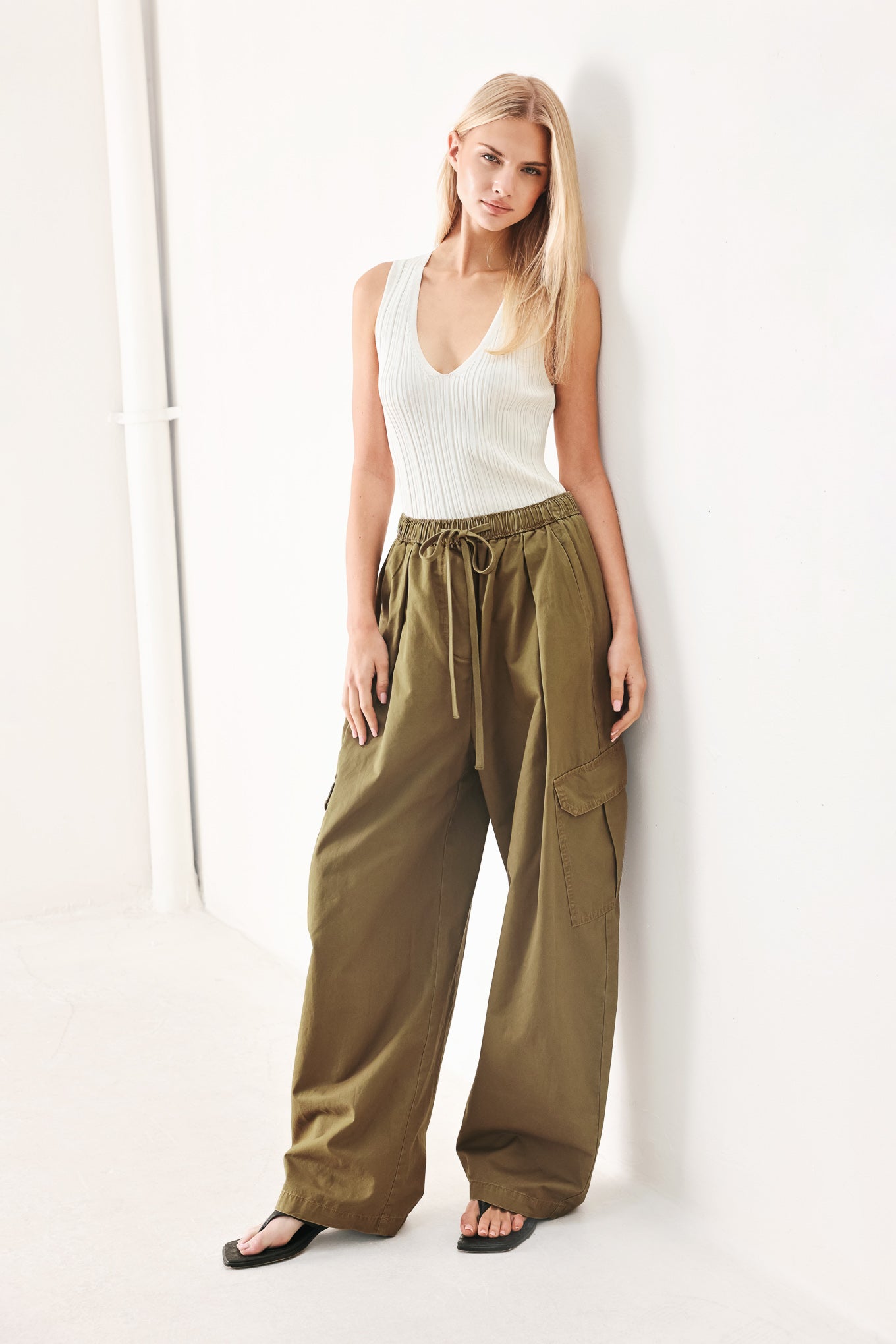 Woman wearing olive green wide-leg woven barrel pants with an elastic waist with contrasting tie and cargo pockets | FREEMARKET