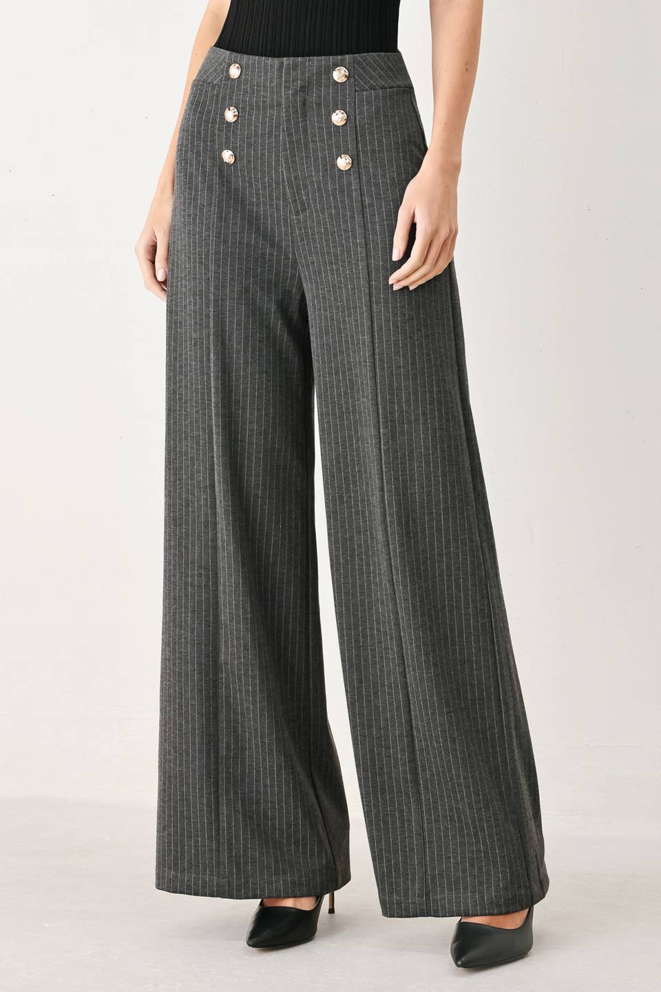Woman wearing high-waisted, wide-leg charcoal gray and white pinstriped trousers with decorative gold-tone buttons on the front waistband | FREEMARKET