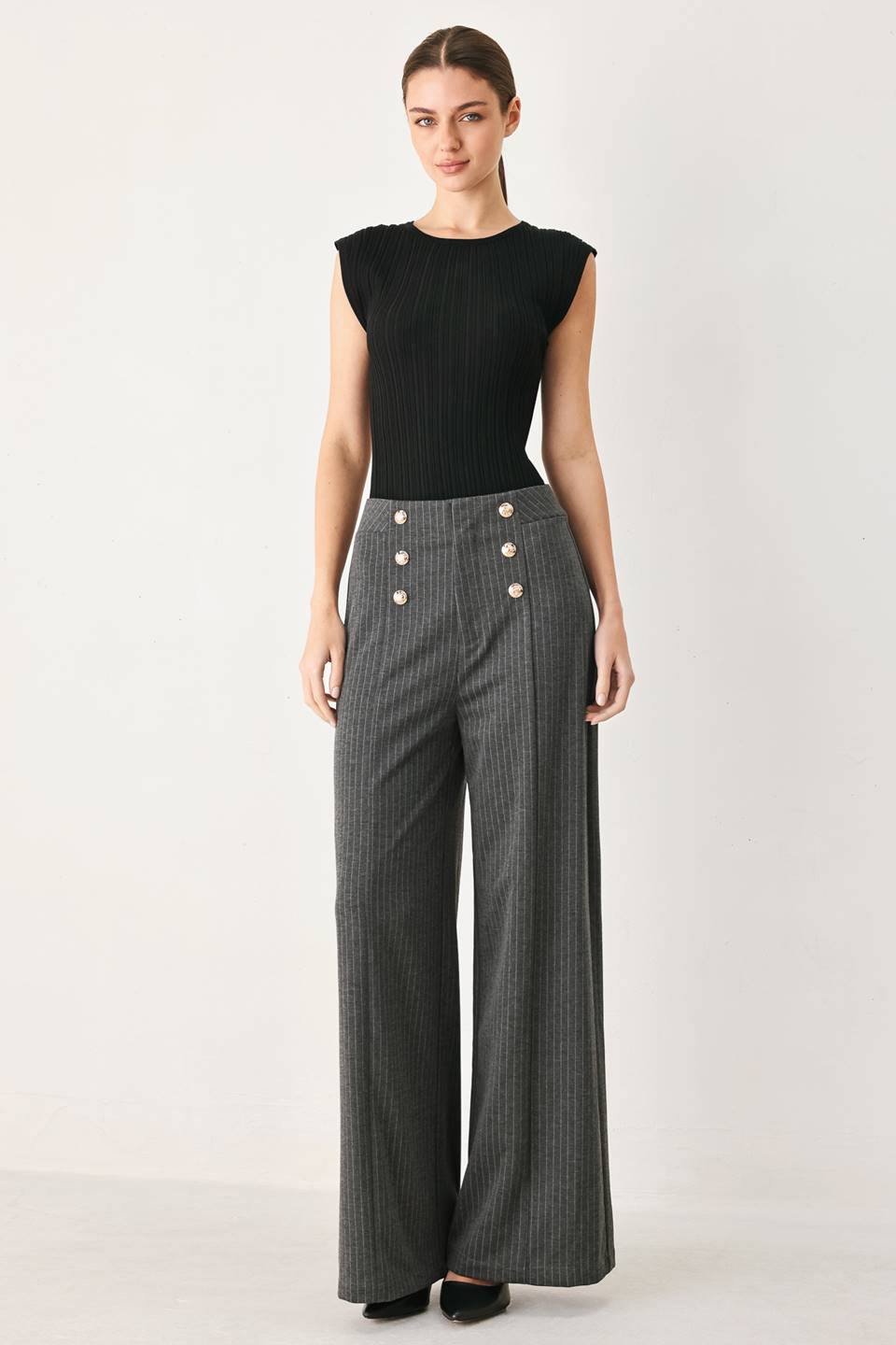 Woman wearing high-waisted, wide-leg charcoal gray and white pinstriped trousers with decorative gold-tone buttons on the front waistband | FREEMARKET