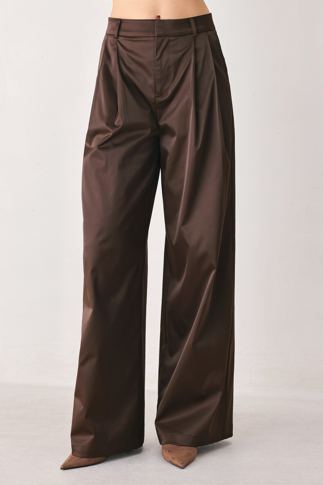 A person wearing high-waisted, wide-leg brown trousers with a glossy finish | FREEMARKET