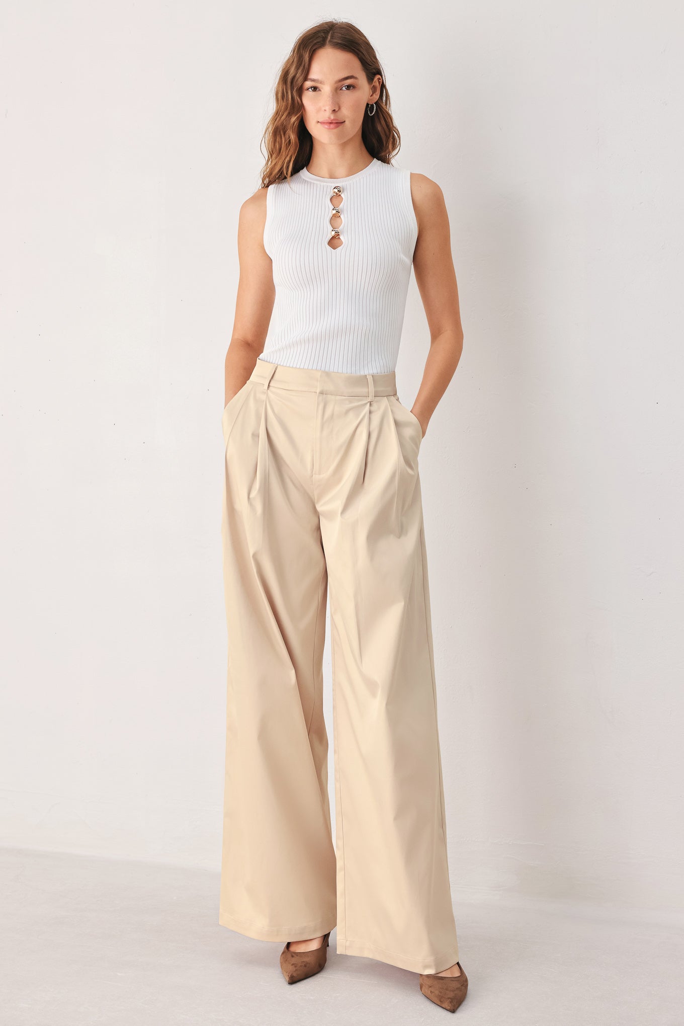 A person wearing high-waisted, wide-leg champagne trousers with a glossy finish | FREEMARKET