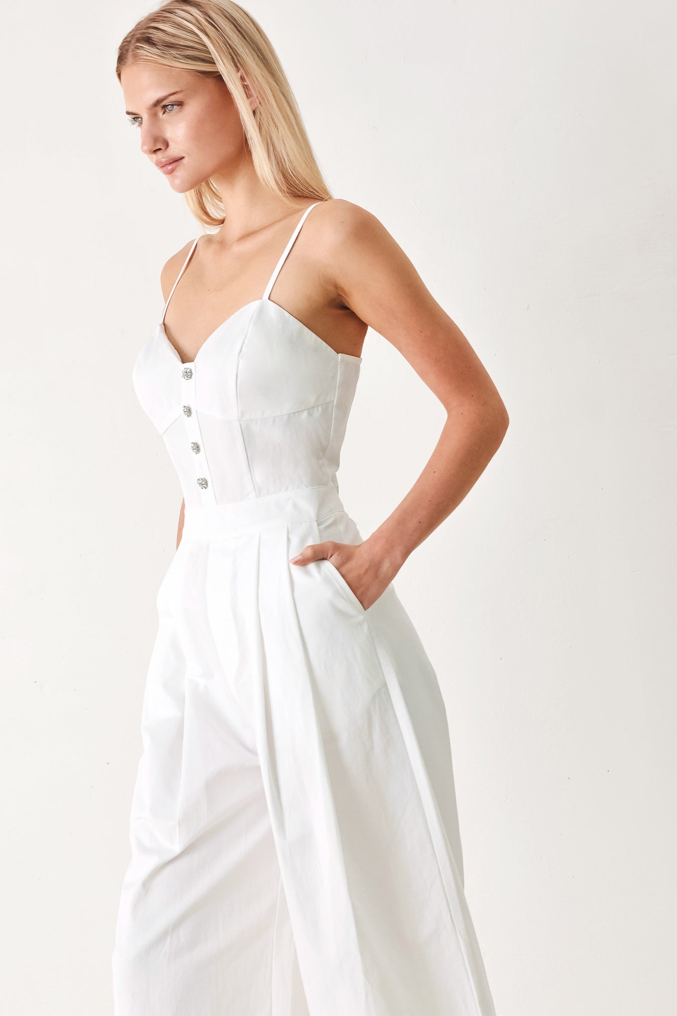 Woman wearing a white jumpsuit with front button detail, straps, side pockets, wide leg and back zipper closure | FREEMARKET