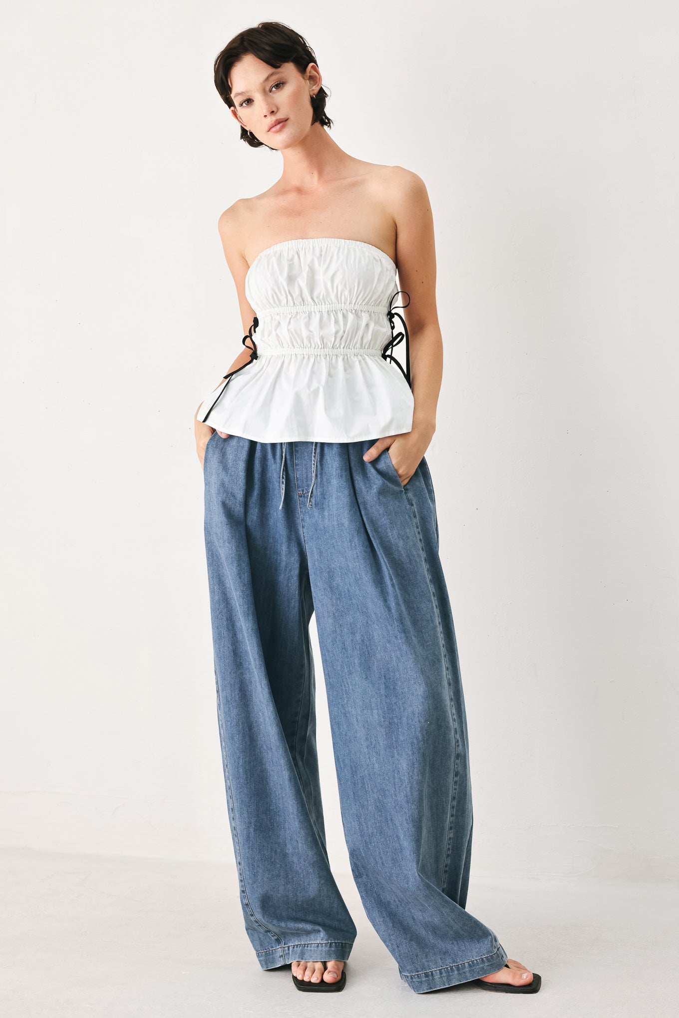 Woman wearing blue denim wide-leg pants with pockets and elastic waist with tie | FREEMARKET