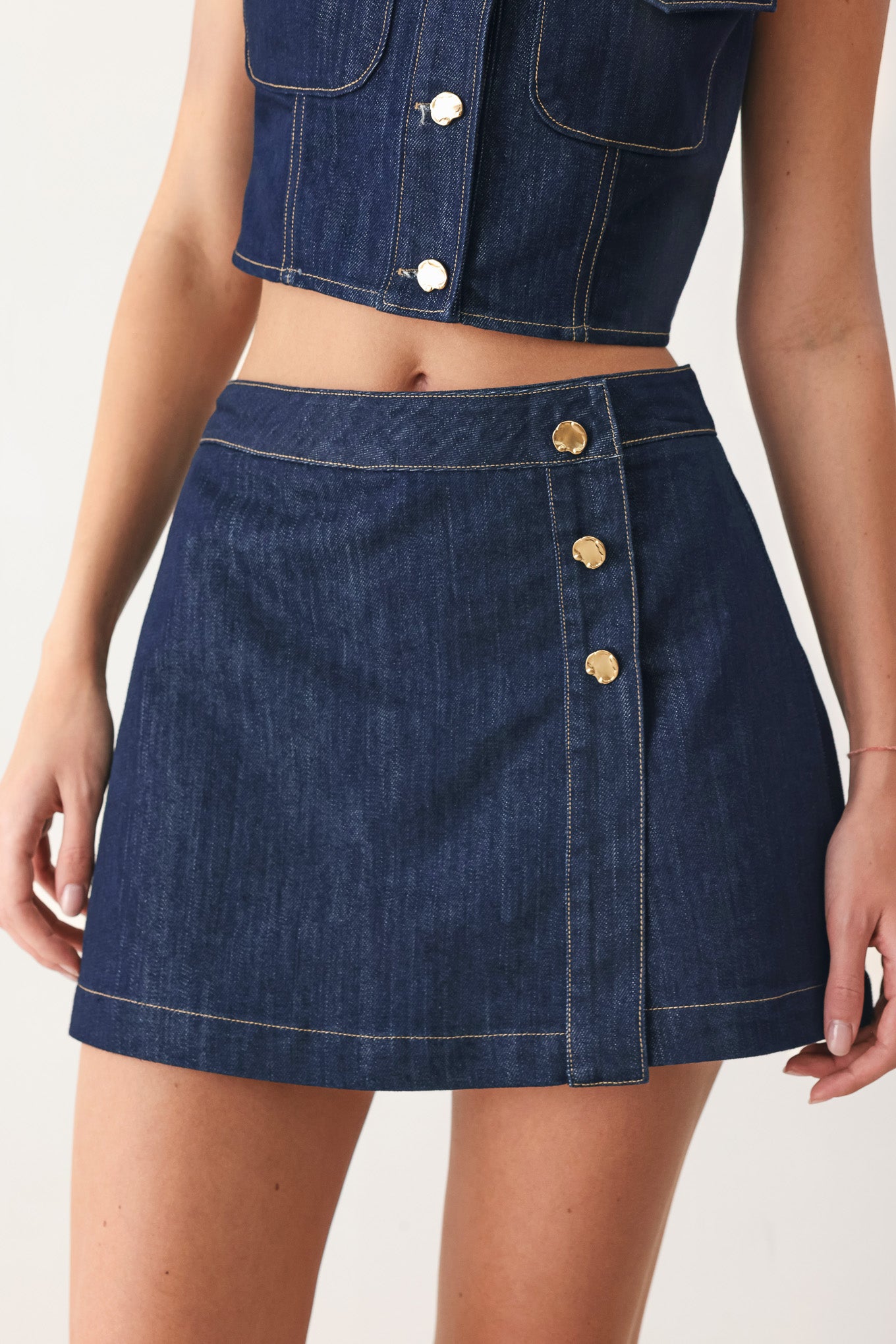 Woman wearing a blue denim denim skort with front closure and button detail | FREEMARKET