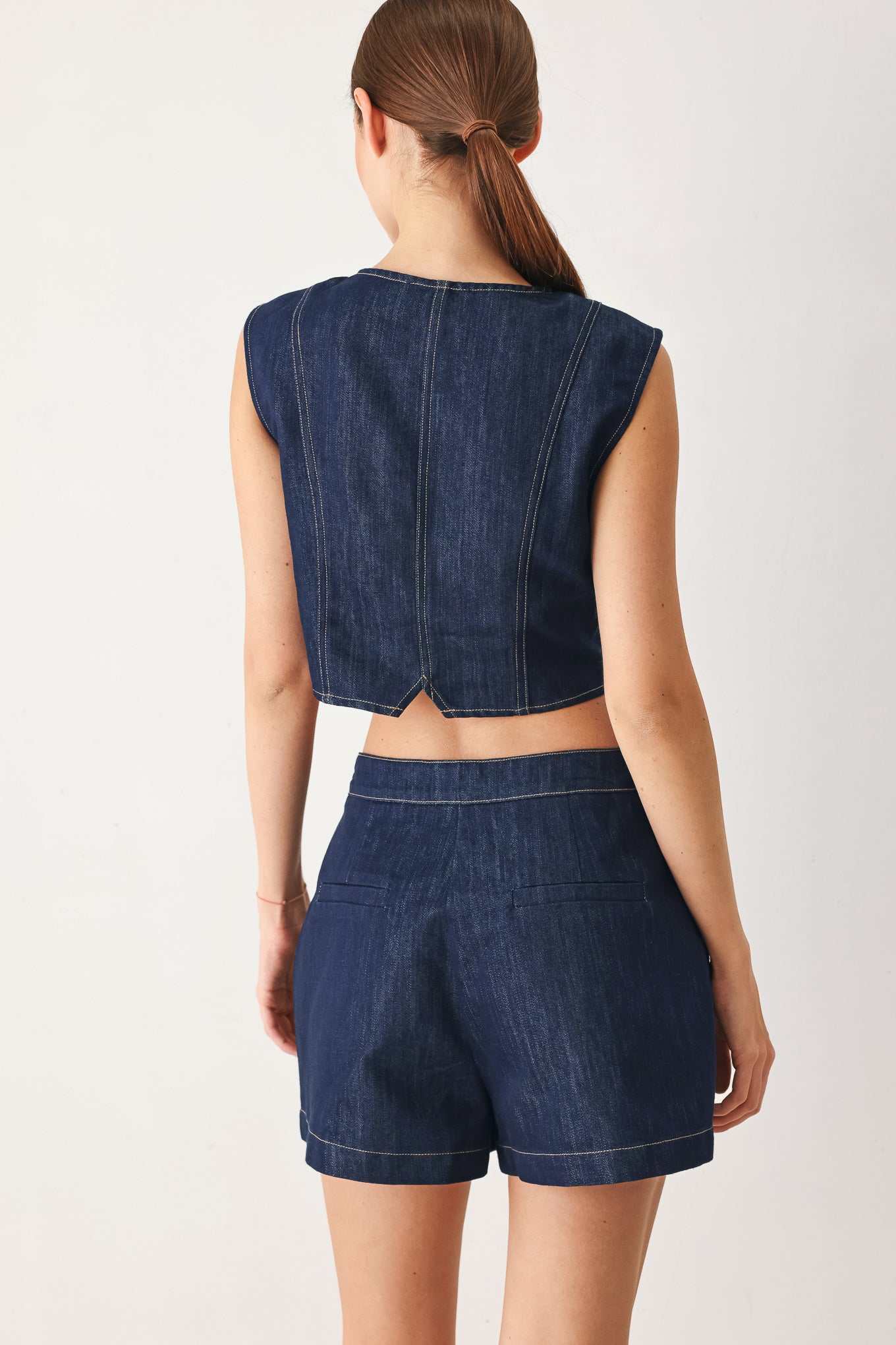 Woman wearing a blue denim denim skort with front closure and button detail | FREEMARKET
