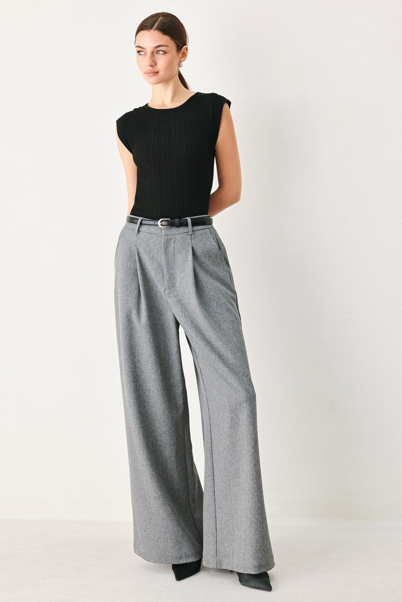 Woman wearing gray wide-leg pant with front closure, single pleat, pockets, and black belt | FREEMARKET