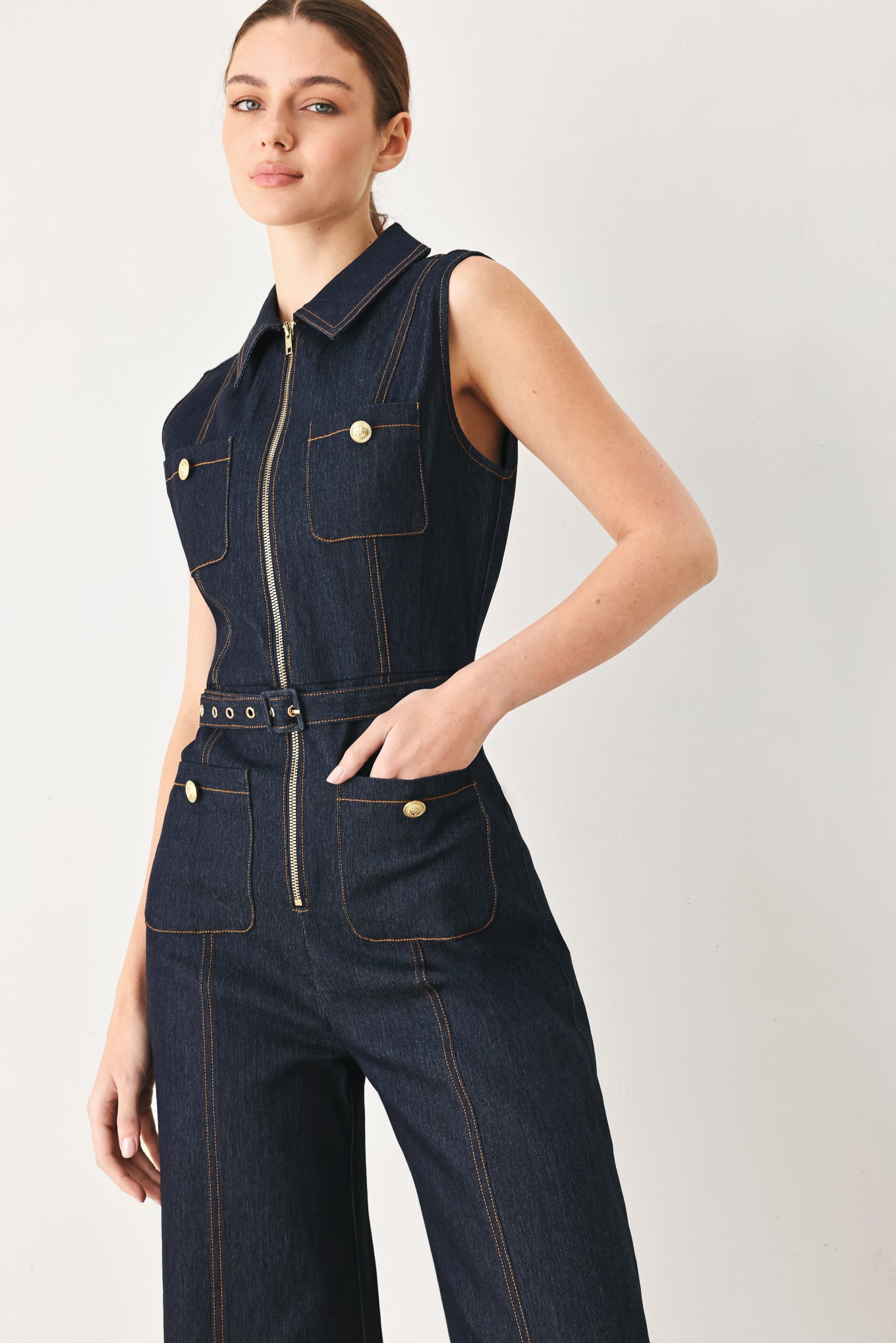 Woman wearing a dark blue denim sleeveless, wide-leg jumpsuit featuring collar, front zipper closure, and pockets | FREEMARKET