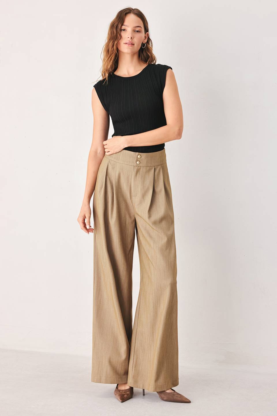 A model wearing high-waisted, wide-leg trousers in a light tan color with buttons | FREEMARKET