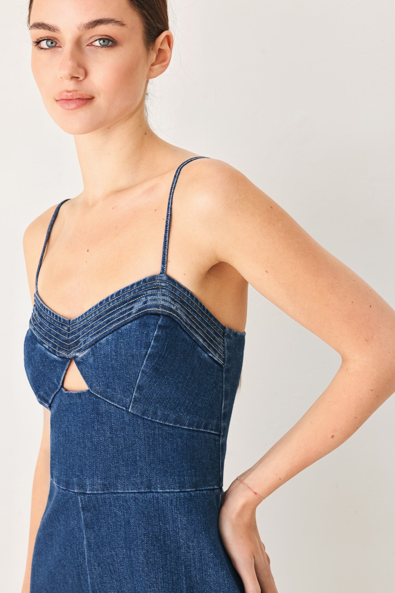 Woman wearing a blue denim jumpsuit featuring cami top with cut out, wide leg and back zipper closure | FREEMARKET