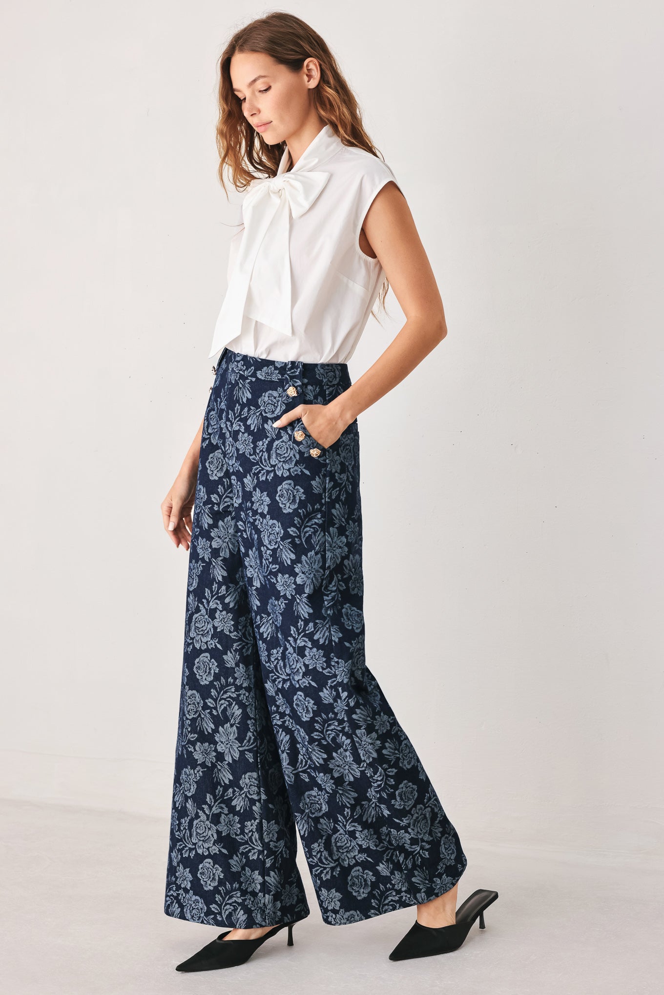 A woman wearing navy wide-leg jacquard pants with a light blue floral pattern and decorative buttons on the side | FREEMARKET