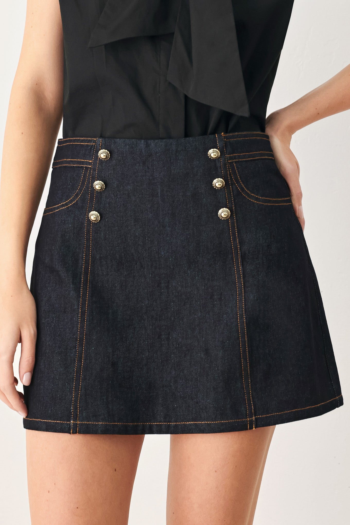 Woman wearing a dark lightweight denim skort with front button detail, pockets and back zipper closure | FREEMARKET