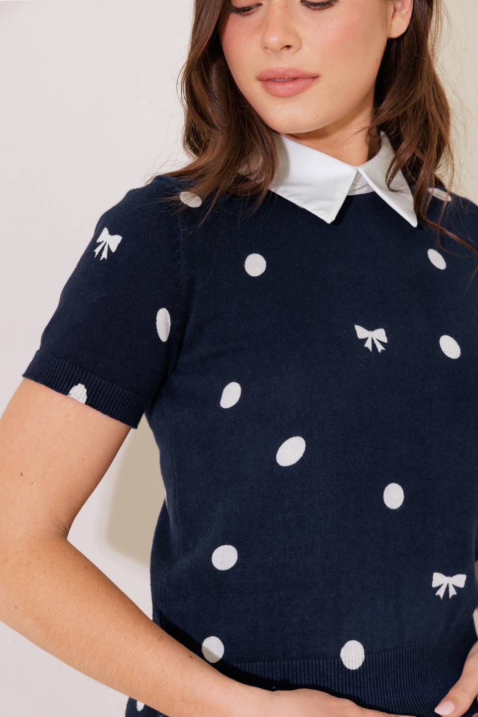 A sweater knit top featuring woven collar back button closure and short sleeve