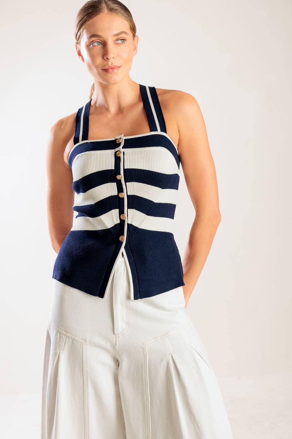 A navy and white striped sweater knit top featuring a halter neckline button down closure and cross back strap.