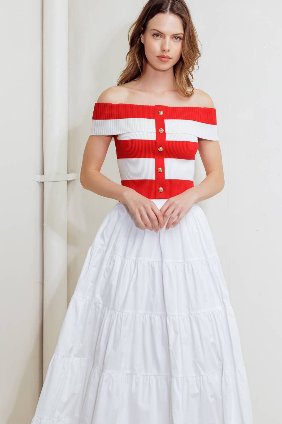 A red and white striped sweater knit crop top featuring off shoulder neckline and button down detail