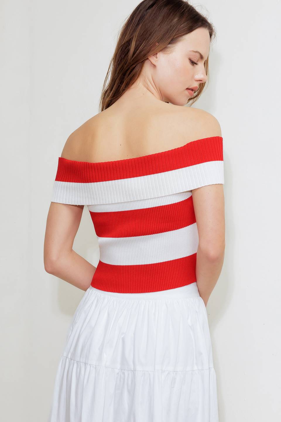 A red and white striped sweater knit crop top featuring off shoulder neckline and button down detail