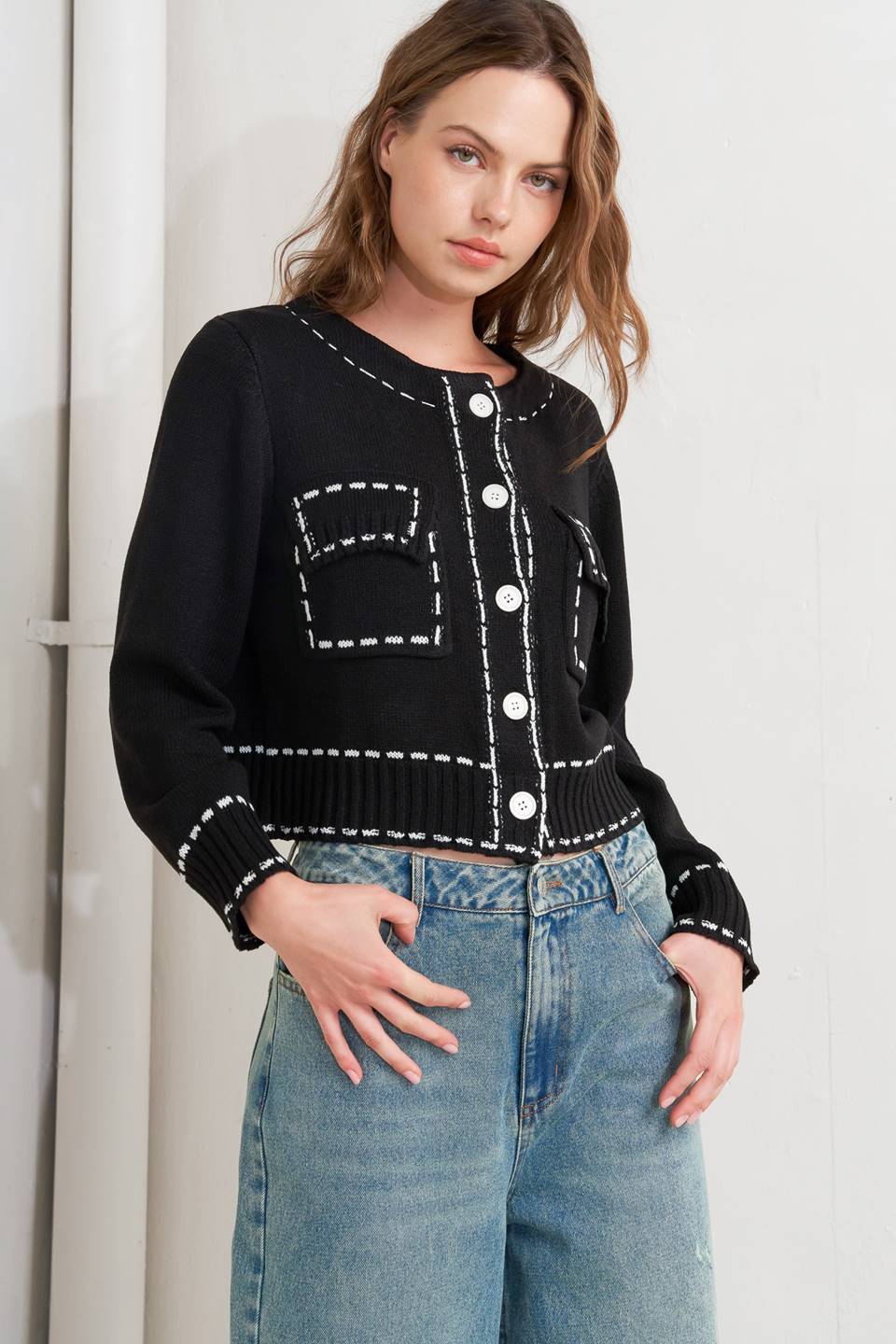 A sweater knit top featuring round neckline, button down, long sleeve and stitch edge detail