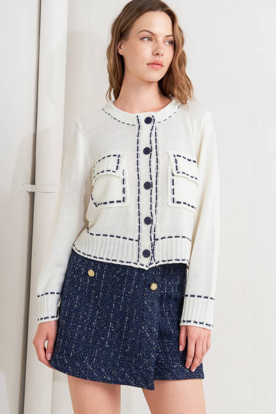 A sweater knit top featuring round neckline, button down, long sleeve and stitch edge detail