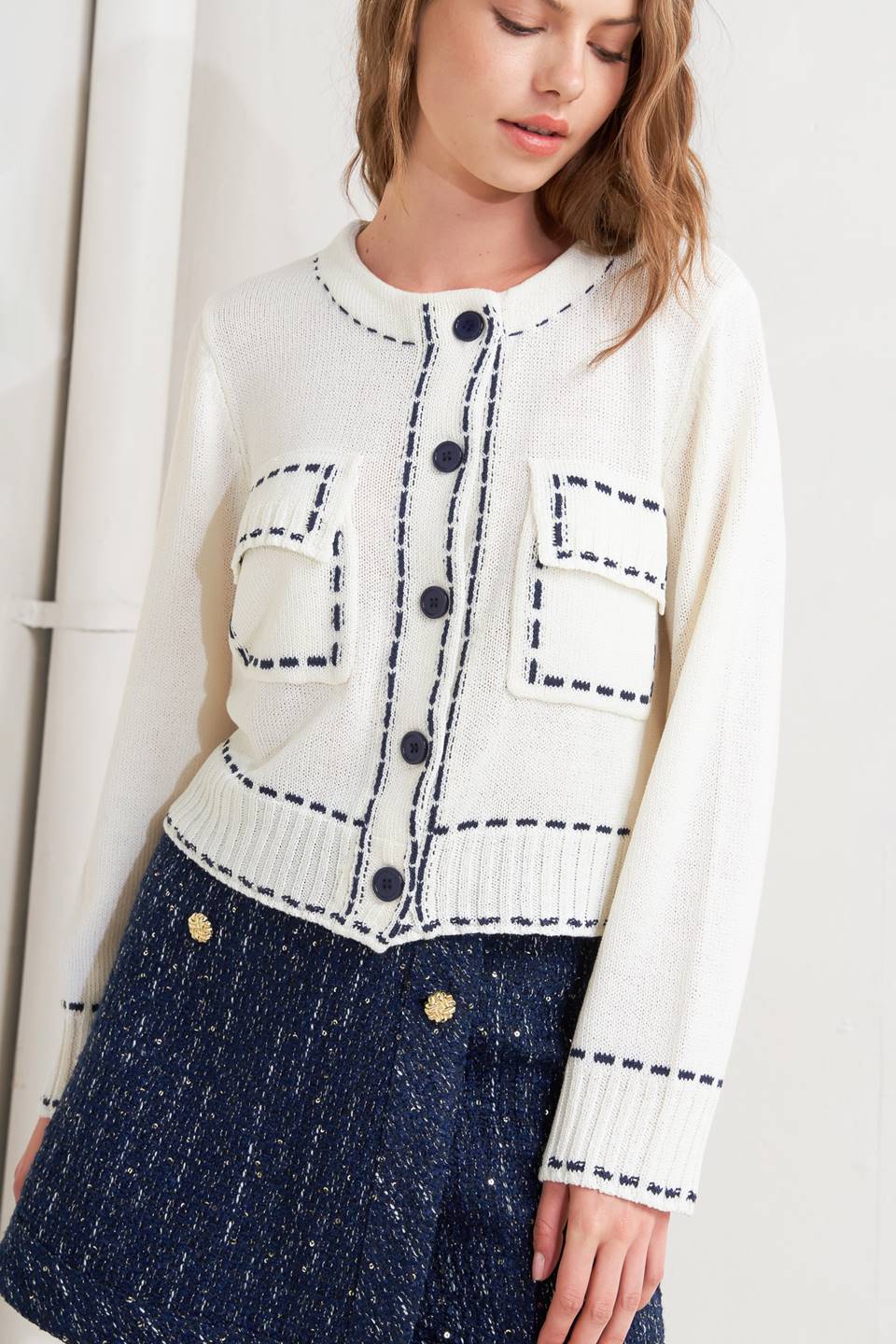 A sweater knit top featuring round neckline, button down, long sleeve and stitch edge detail