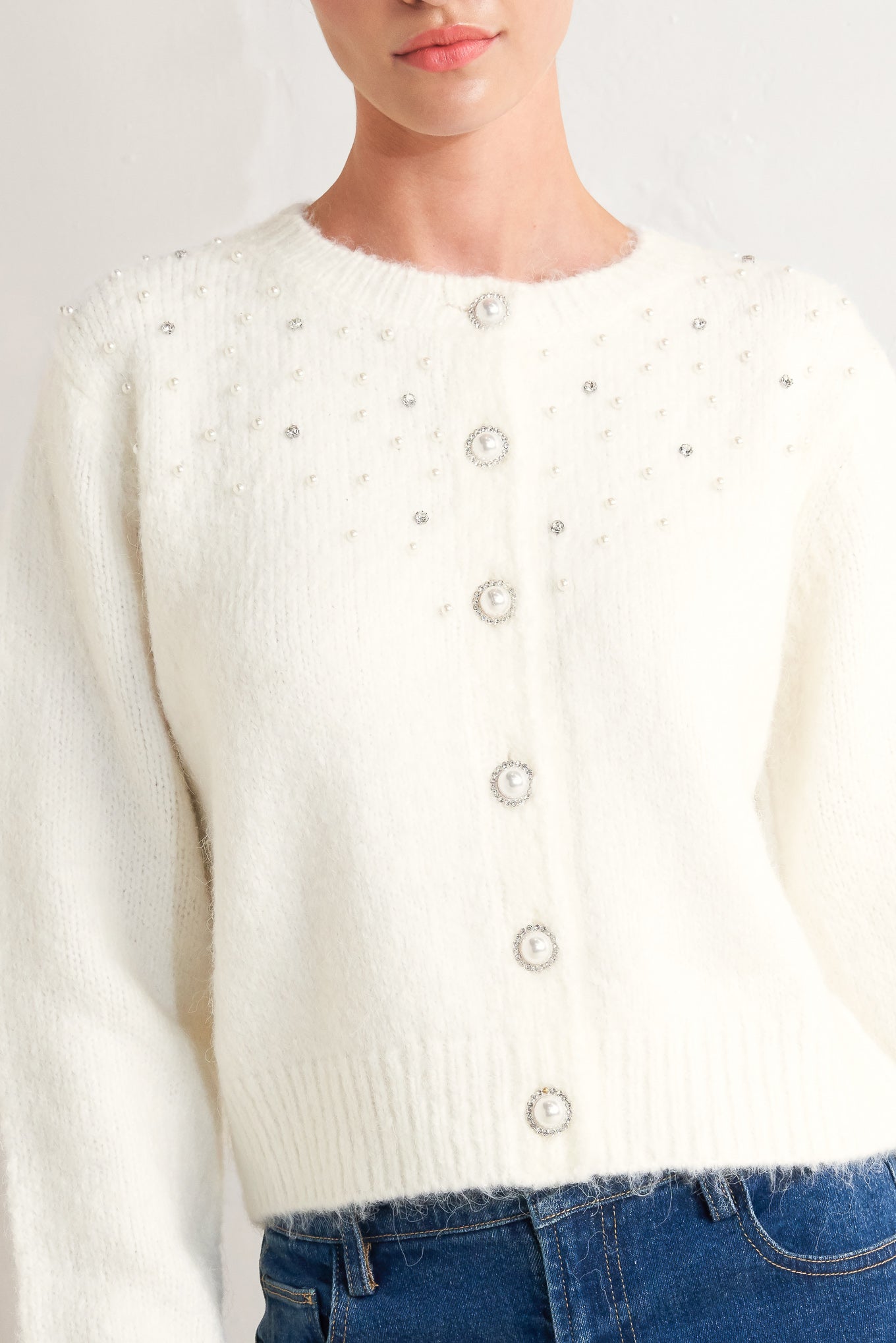A sweater knit cardigan featuring round neckline, long sleeve and jewel embellishment and button
