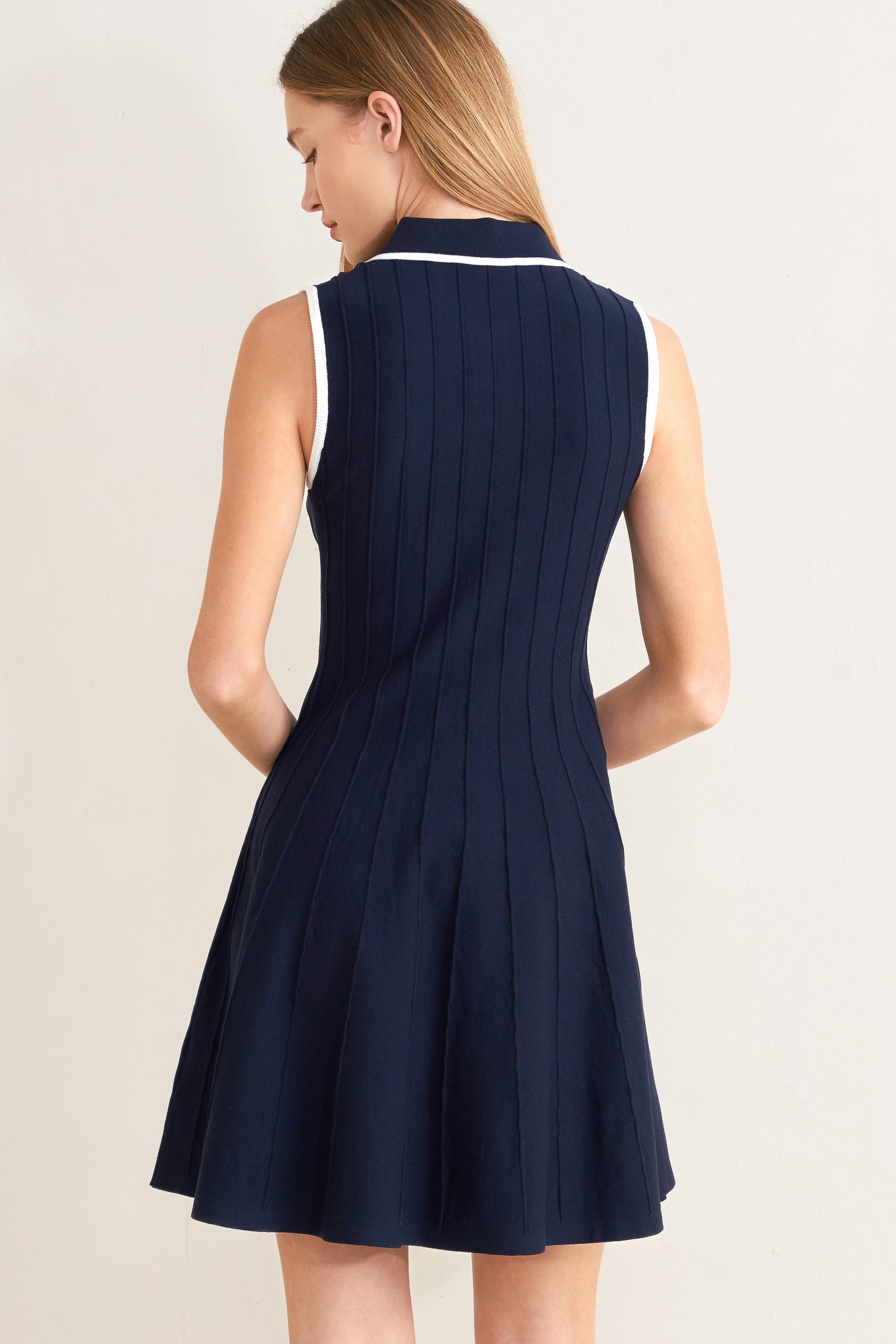 Navy blue dress with white trim on a plain background
