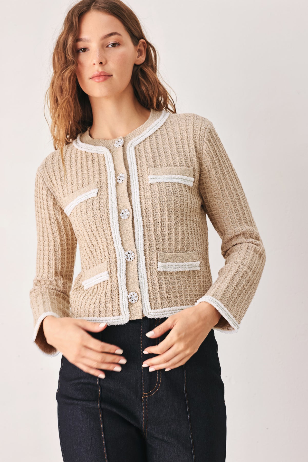 A woman wearing a beige textured knit cardigan with white trim and decorative buttons | FREEMARKET