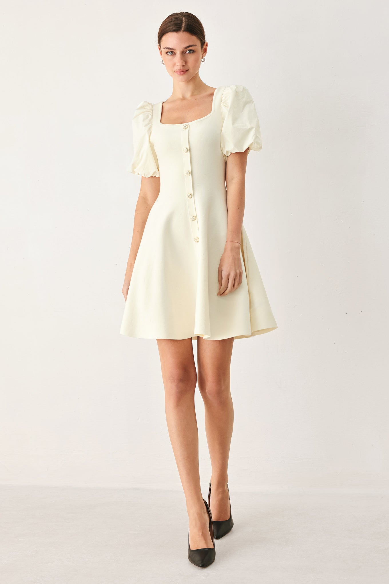 Woman wearing a light ivory sweater knit mini dress with puff sleeves featuring U neckline and front button down | FREEMARKET