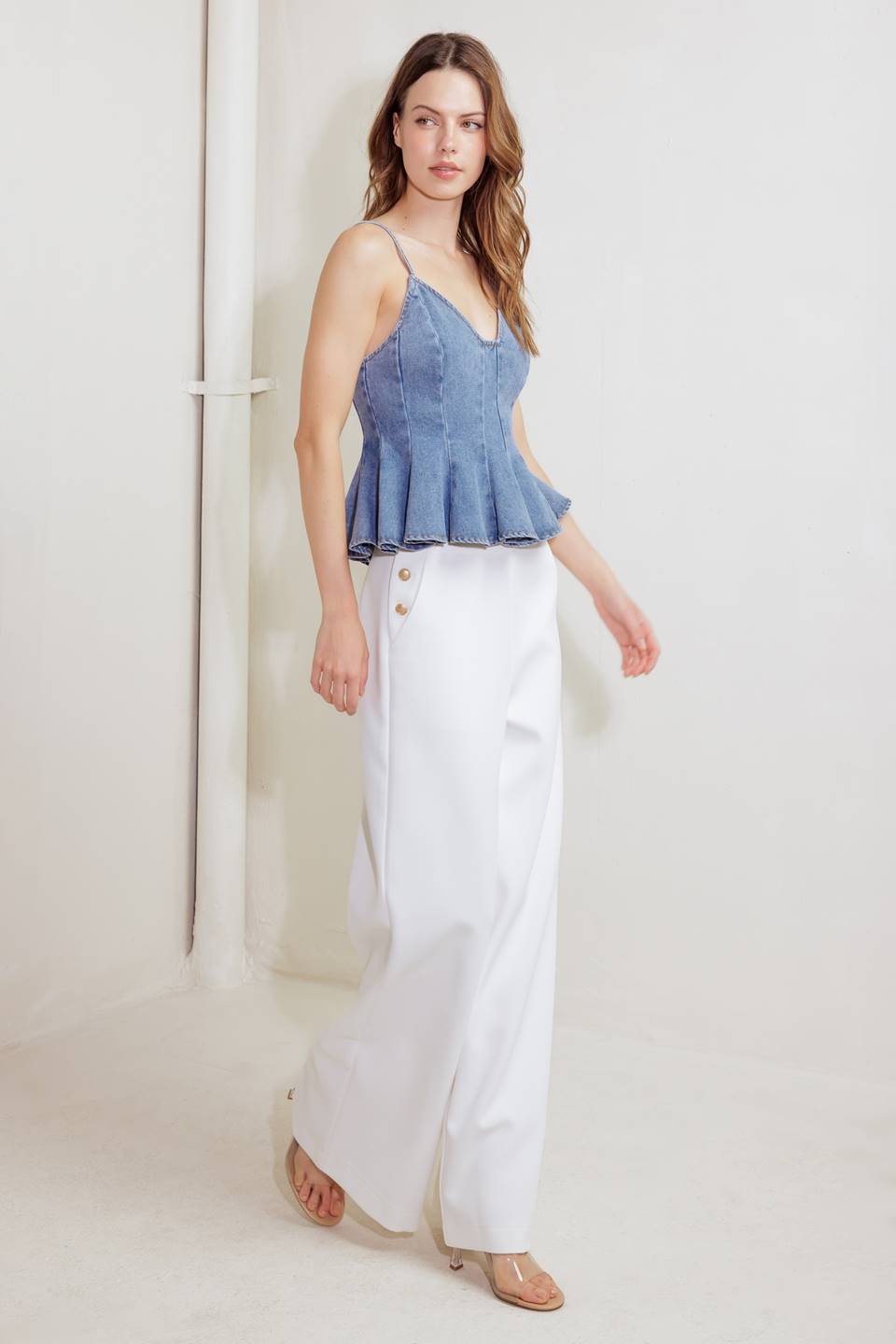 A washed denim cami top featuring straps, peplum and back zipper closure.