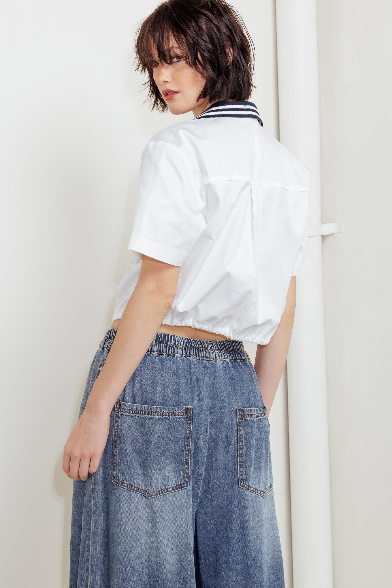 A woven crop top featuring contrasting collar, button down and waist drawstring.