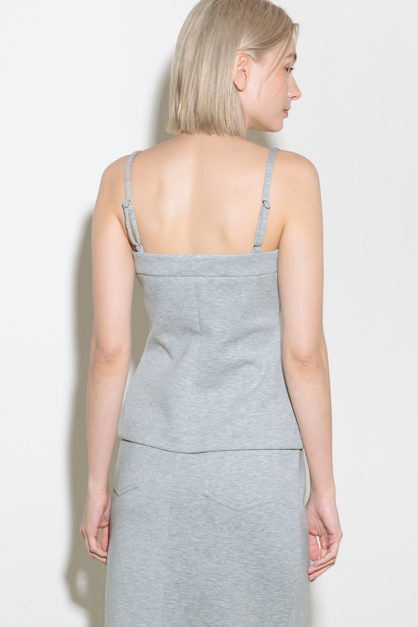 A solid knit top featuring straight neckline, straps and front button down.