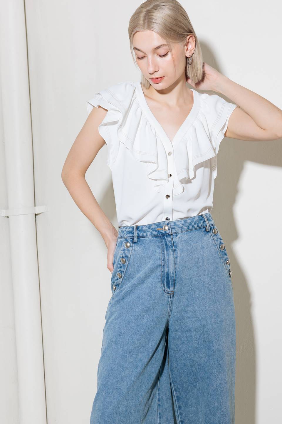 A solid woven top featuring V neckline, ruffles and button down.