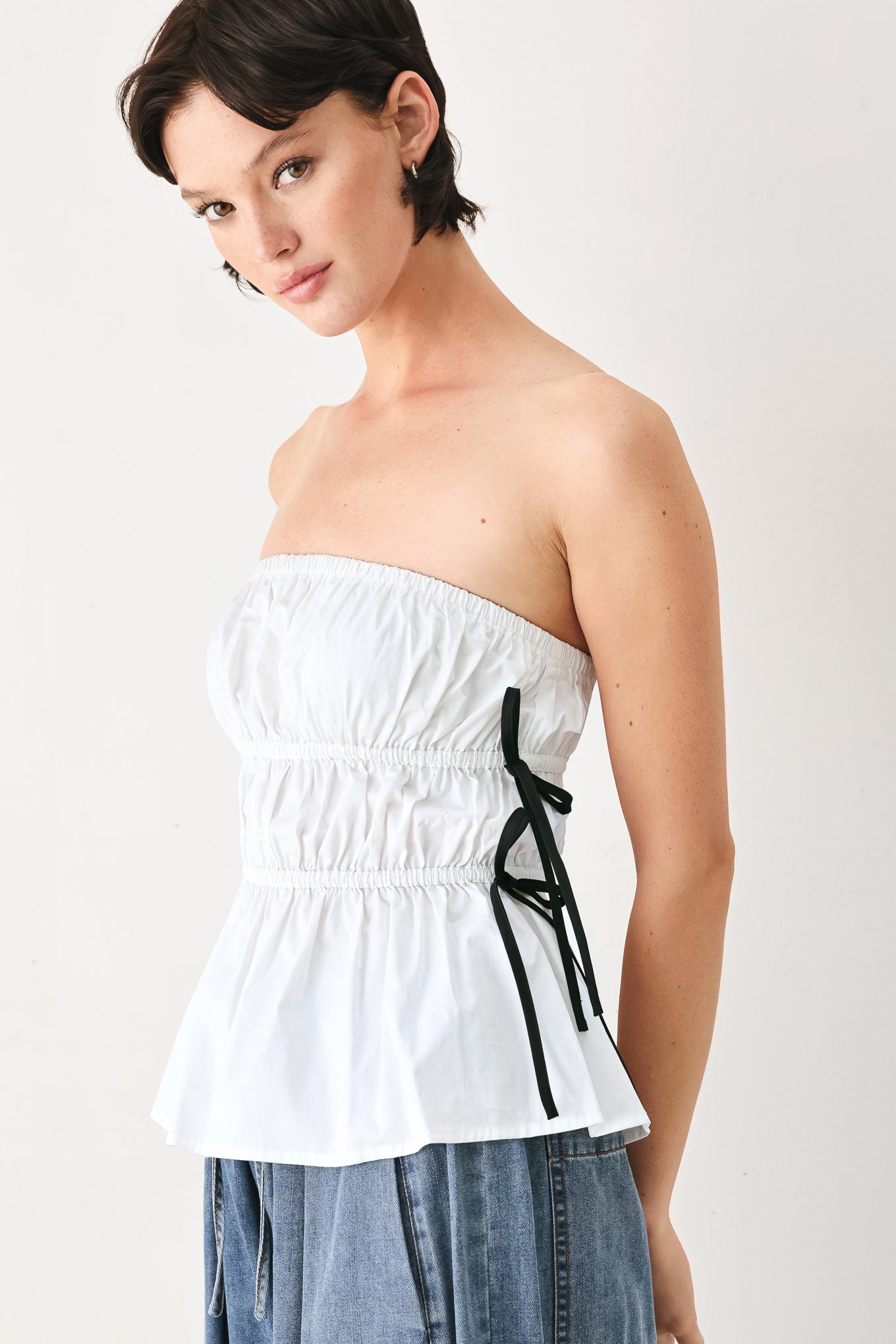 Woman wearing a white strapless top with black side ribbon bow ties | FREEMARKET